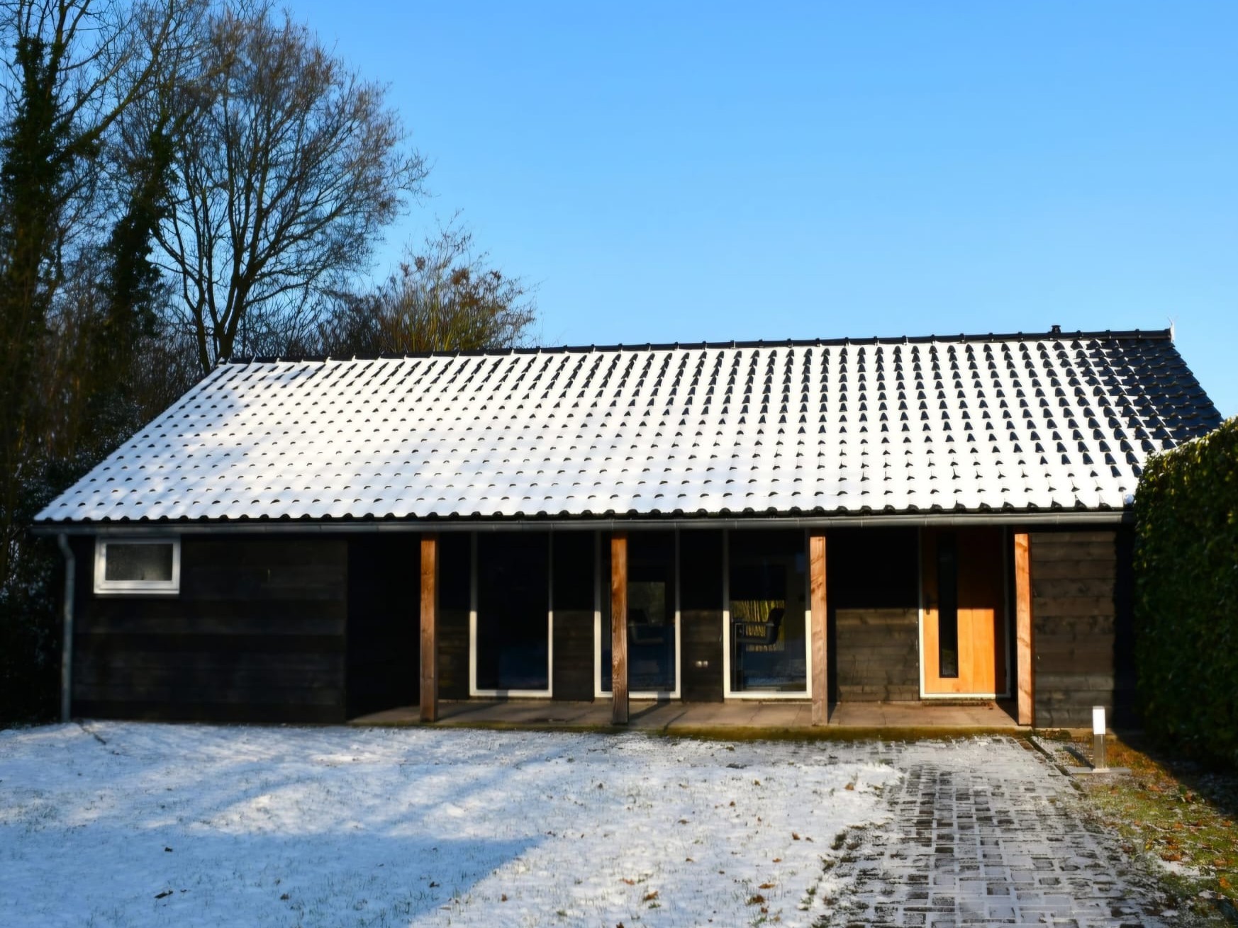 Het luxe zomerhuisje van De Watertoren op een heldere winterochtend, met een besneeuwd pannendak en een overdekt terras